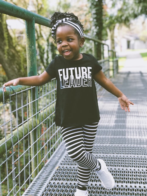 A smiling preschool girl wearing a t-shirt that says future leader