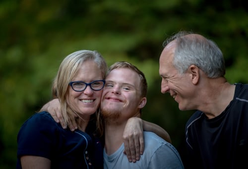 Parents smiling and hugging their son with special needs