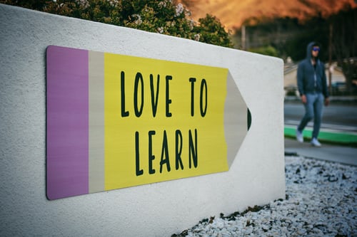 A wall with a pencil shaped sign that says love to learn