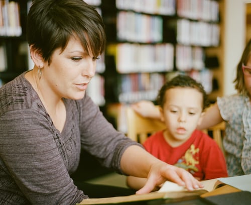A parent reading to a young child in a classroom